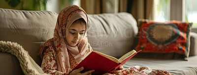 Buy stock photo Muslim, religion and child reading Quran in home on sofa for faith or worship on EID in living room. Islam, girl and kid study book for learning, education or spiritual knowledge on ramadan mubarak