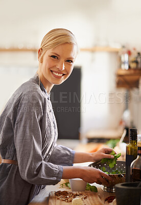 Buy stock photo Portrait of an attractive young woman preparing food in her rustic kitchen