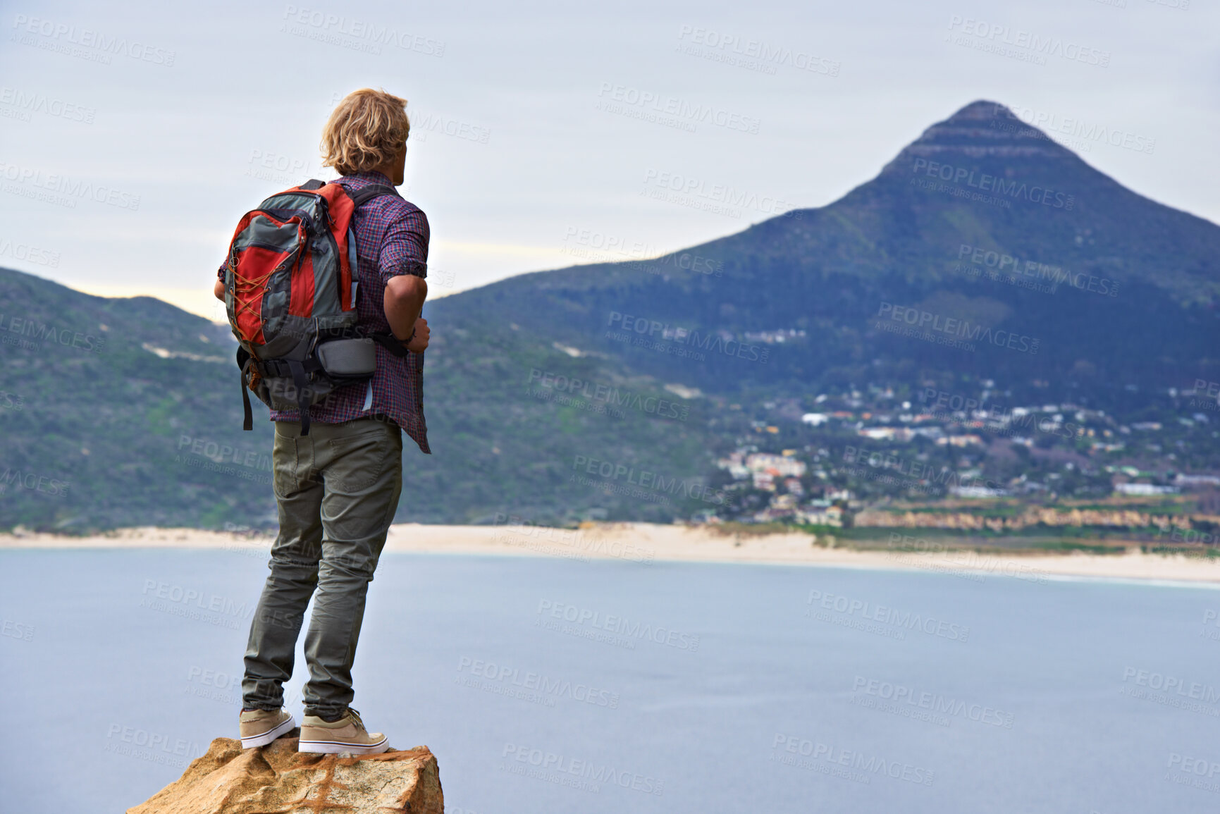 Buy stock photo Man, backpack and hiking on mountain by ocean for travel, sightseeing or outdoor journey in nature. Rear view of male person, hiker or tourist with bag on rock for trekking, fitness or adventure
