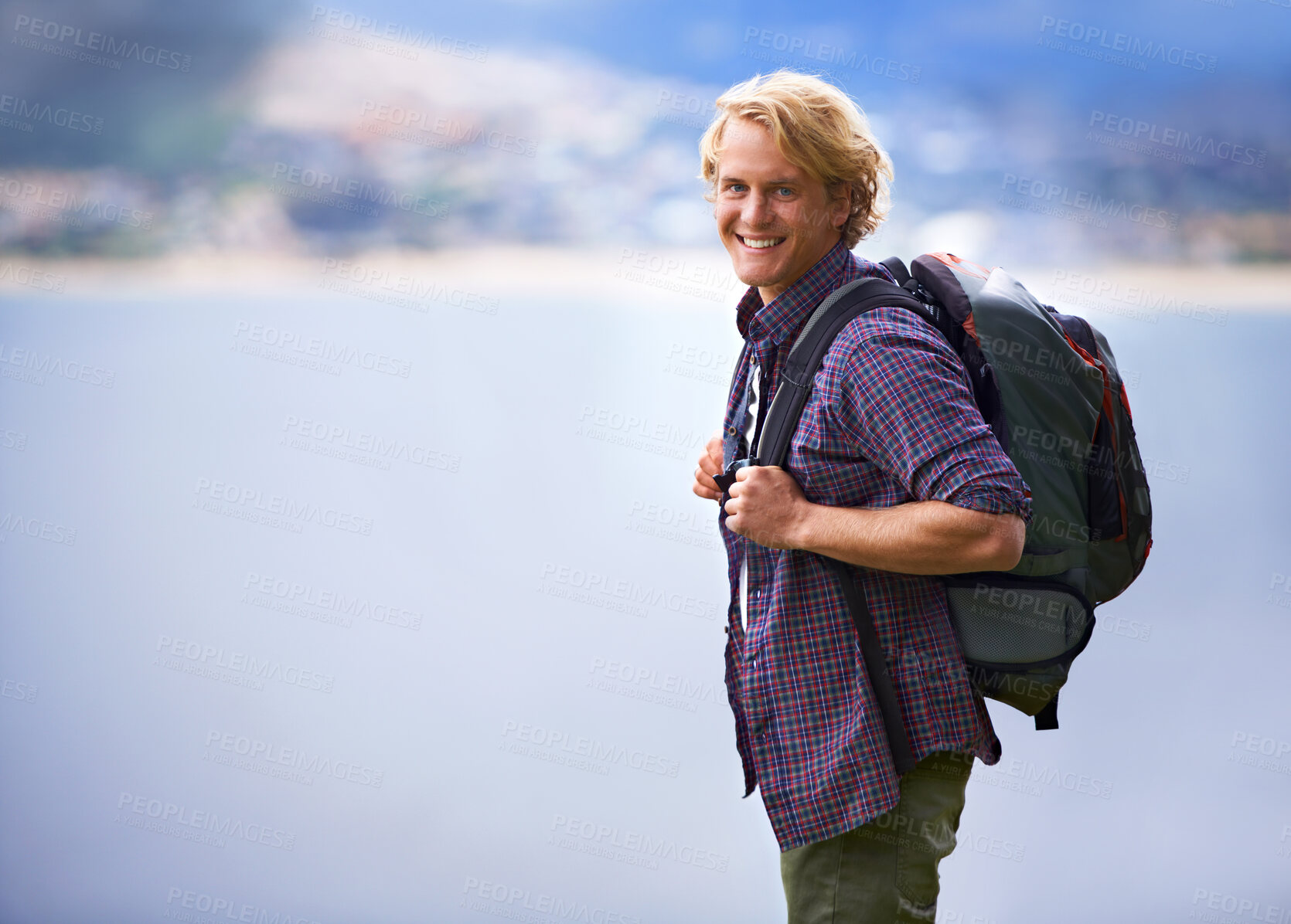 Buy stock photo Man, hiking and portrait in nature for travel, adventure and wellness by ocean, sea and vacation in Europe. Face of an happy and young person with backpack for trekking, explore and outdoor journey