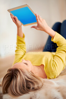 Buy stock photo A rear view shot of a young woman using a digital tablet at home