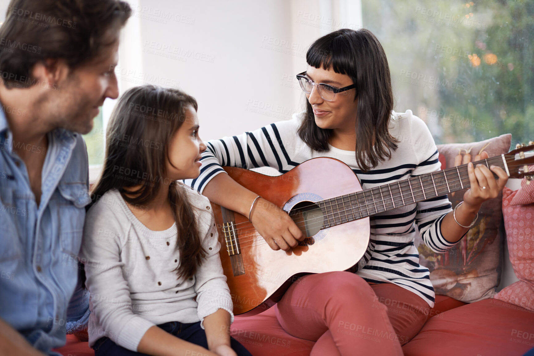 Buy stock photo Woman, music and playing guitar in living room for family, relaxing and enjoying together on couch. Performance, men and child with smile on sofa, entertainment and mother with musical instrument