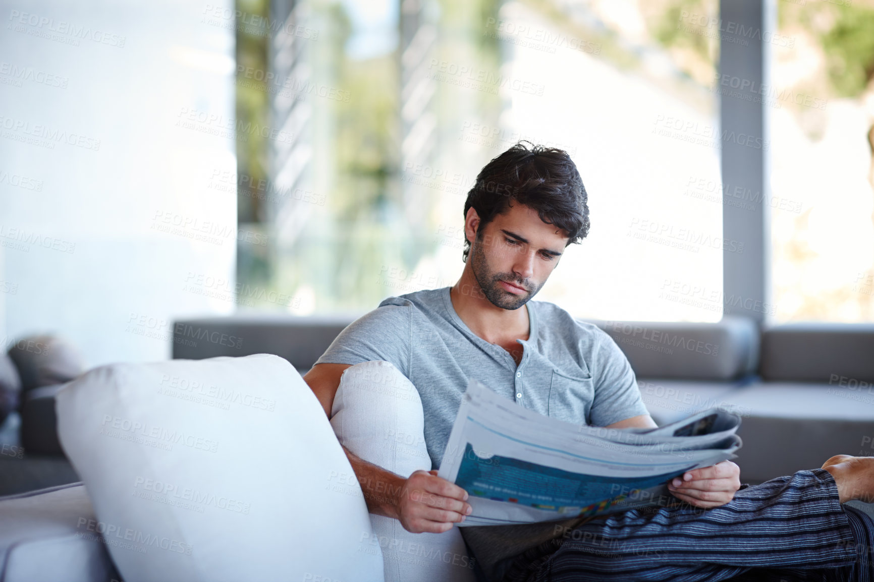 Buy stock photo Home, man and newspaper for reading on sofa in living room for information, story or news. House, lounge and male reader with article on vacation, holiday and weekend trip in London to relax on couch