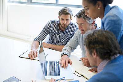 Buy stock photo A group of business colleagues discussing work on a laptop during a boardroom meeting