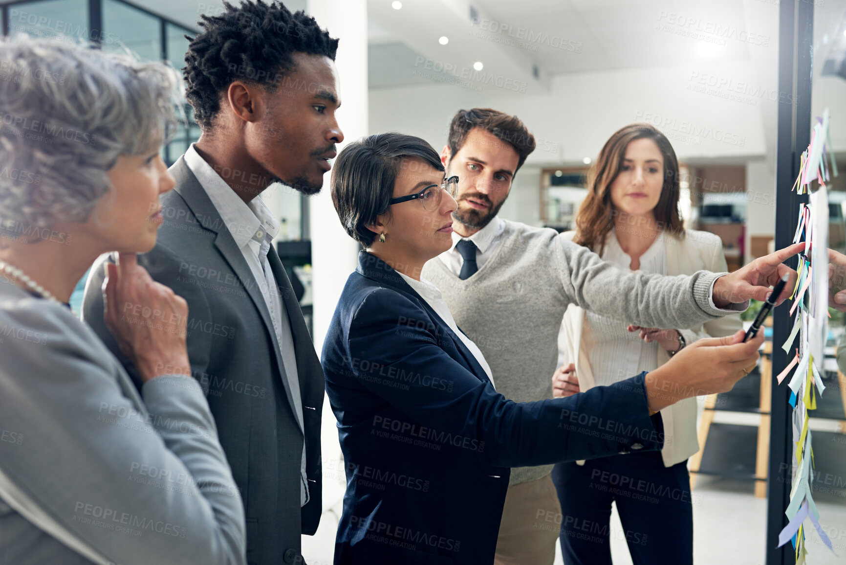 Buy stock photo Shot of a group of businesspeople brainstorming on a glass wall in an office