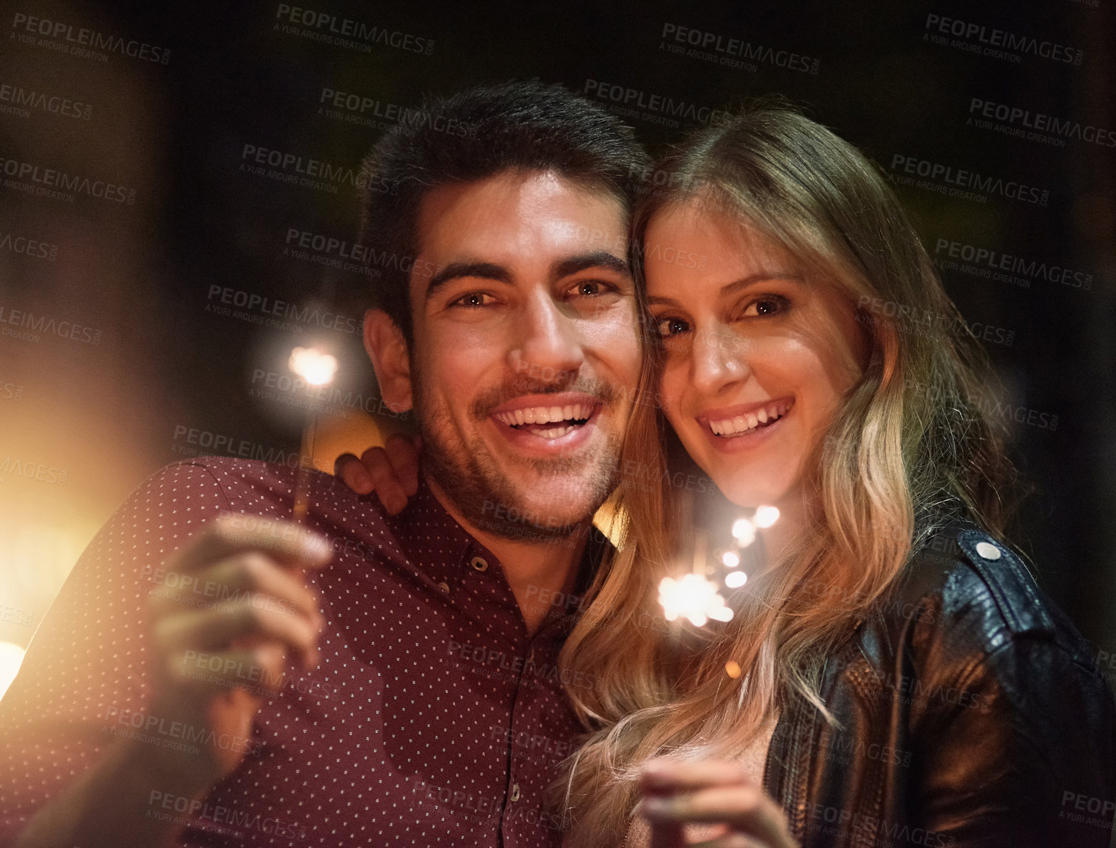 Buy stock photo Portrait, happy couple and sparklers at night for party, celebration and event together outdoor in city with light. Face, man and woman with fireworks on holiday, romantic date or laugh on vacation