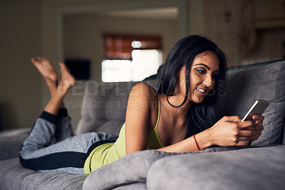 Buy stock photo Couch, rest and Indian girl with phone, typing and relax in living room, smile and chat on social media. Communication, texting and woman with mobile, online and app with internet for person in home