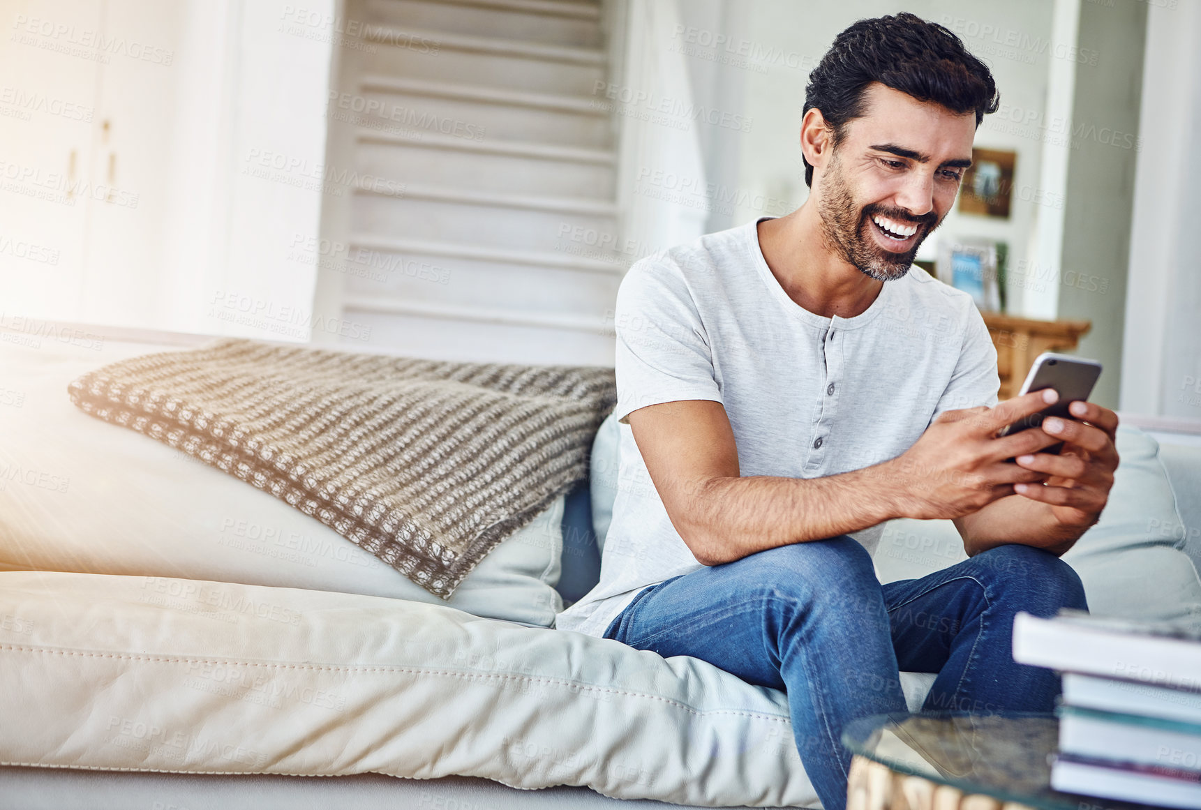 Buy stock photo Man, phone and browsing with smile on sofa for networking, communication or social media in living room. Online, connection and person in lounge for notification, text message or internet app in home