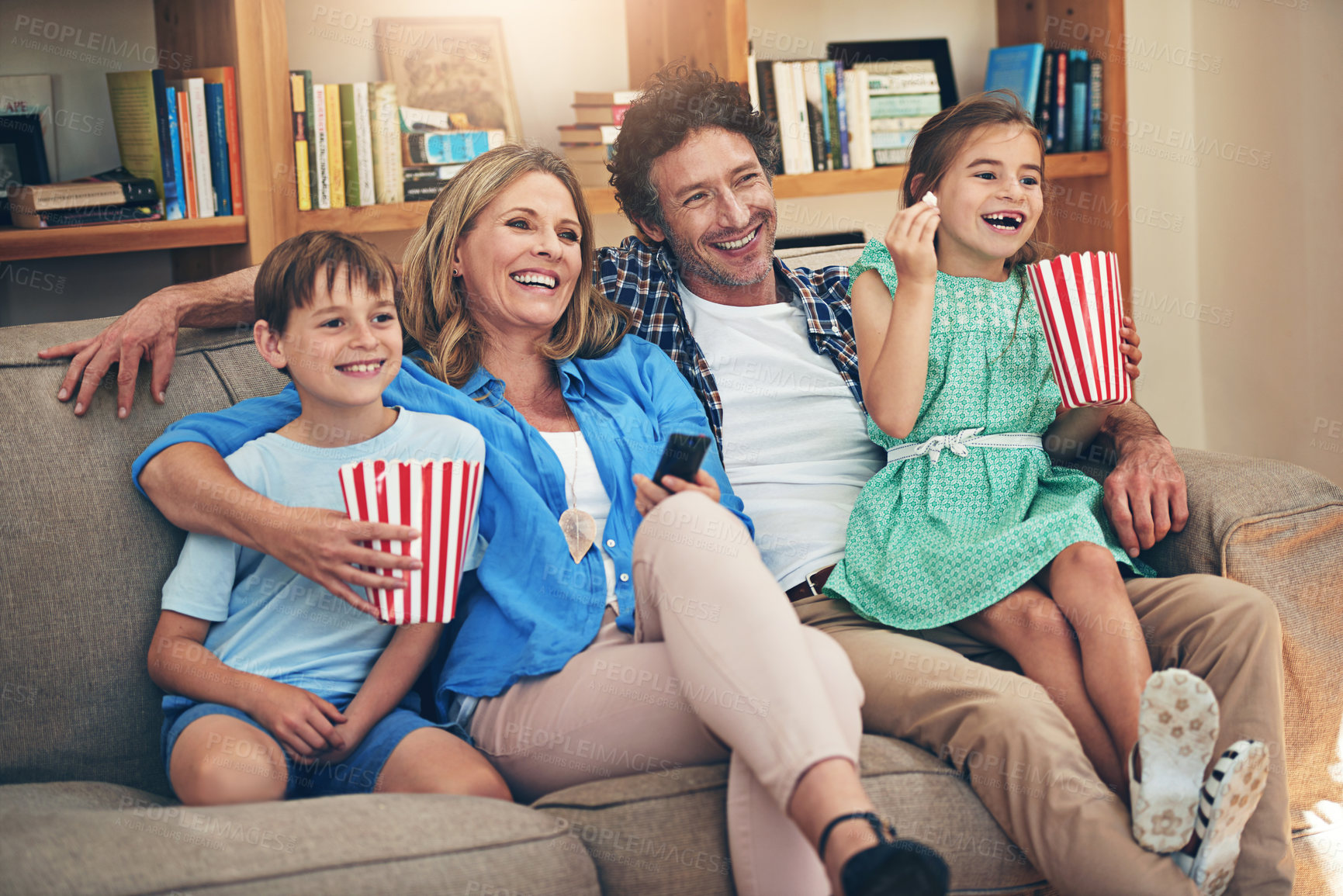 Buy stock photo Happy family, relax and watching tv with popcorn on sofa for movie, weekend or holiday in living room at home. Mom, dad and children with smile and enjoying show, series or streaming service at house
