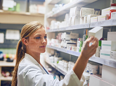 Buy stock photo Shot of a pharmacist looking at medication on a shelf