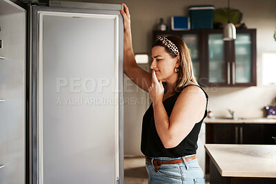 Buy stock photo Shot of a young woman searching inside a refrigerator at home