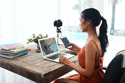 Buy stock photo Cropped shot of an attractive young businesswoman sitting and using her cellphone while blogging from her laptop