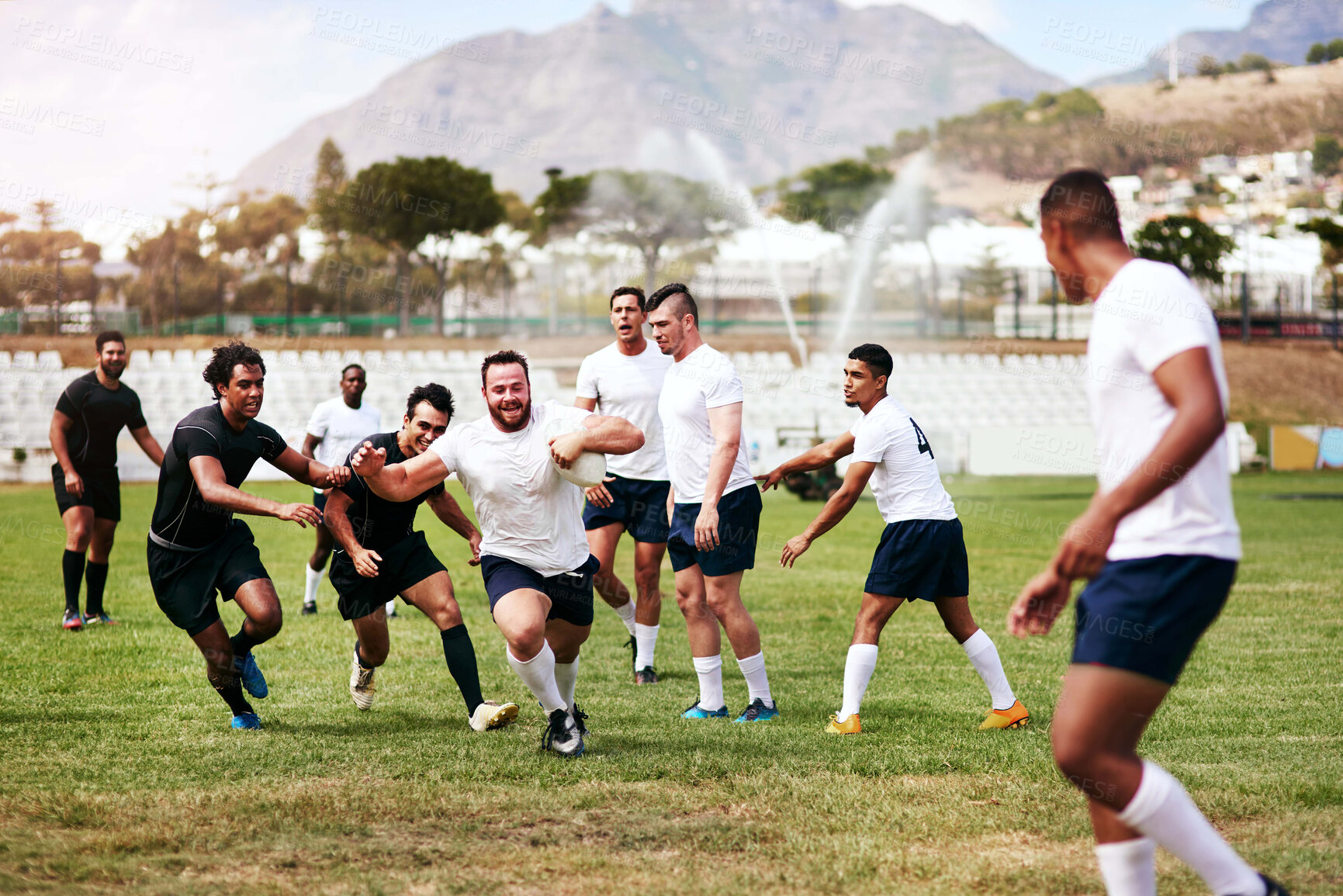 Buy stock photo Shot of a group of young men playing a game of rugby