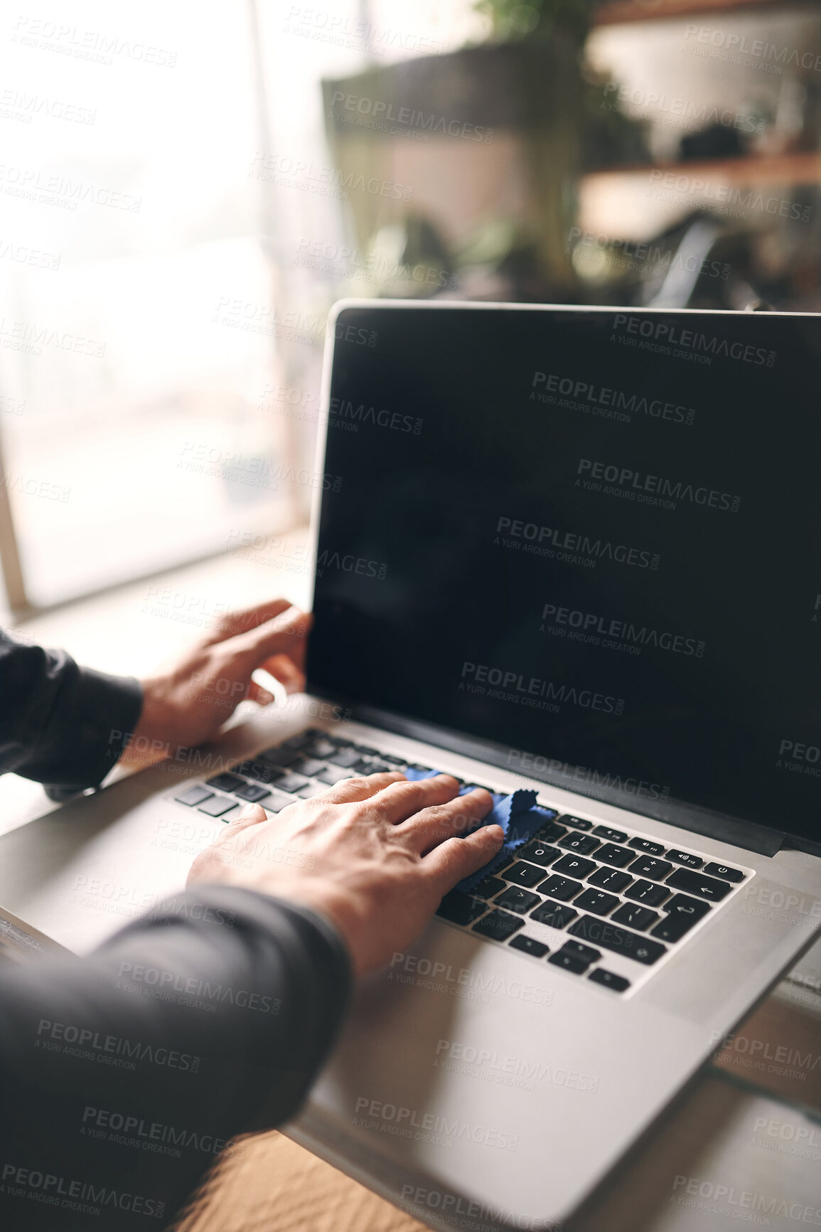 Buy stock photo Cropped shot of an unrecognisable man wiping a laptop with a cloth at home