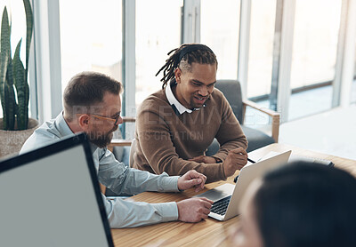 Buy stock photo Cropped shot of two handsome businessmen sitting and using a laptop in the office while their colleagues work around them