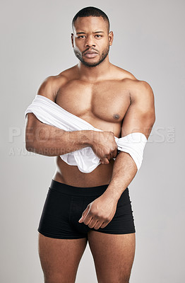 Buy stock photo Strong, African man and taking off shirt in studio with confidence, portrait and fitness in underwear on backdrop. Bodybuilder, athlete and workout for body on grey background with muscles for health
