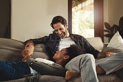 Buy stock photo Shot of a happy young couple relaxing on a sofa and spending time together at home
