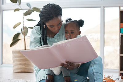 Buy stock photo Shot of a woman reading a book to her daughter while sitting at home