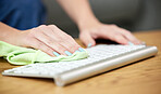 Hands, keyboard and safety with a person cleaning a keyboard on a wooden desk for hygiene. Technology, health or sanitize and an adult wiping a wireless device with a cloth on a table