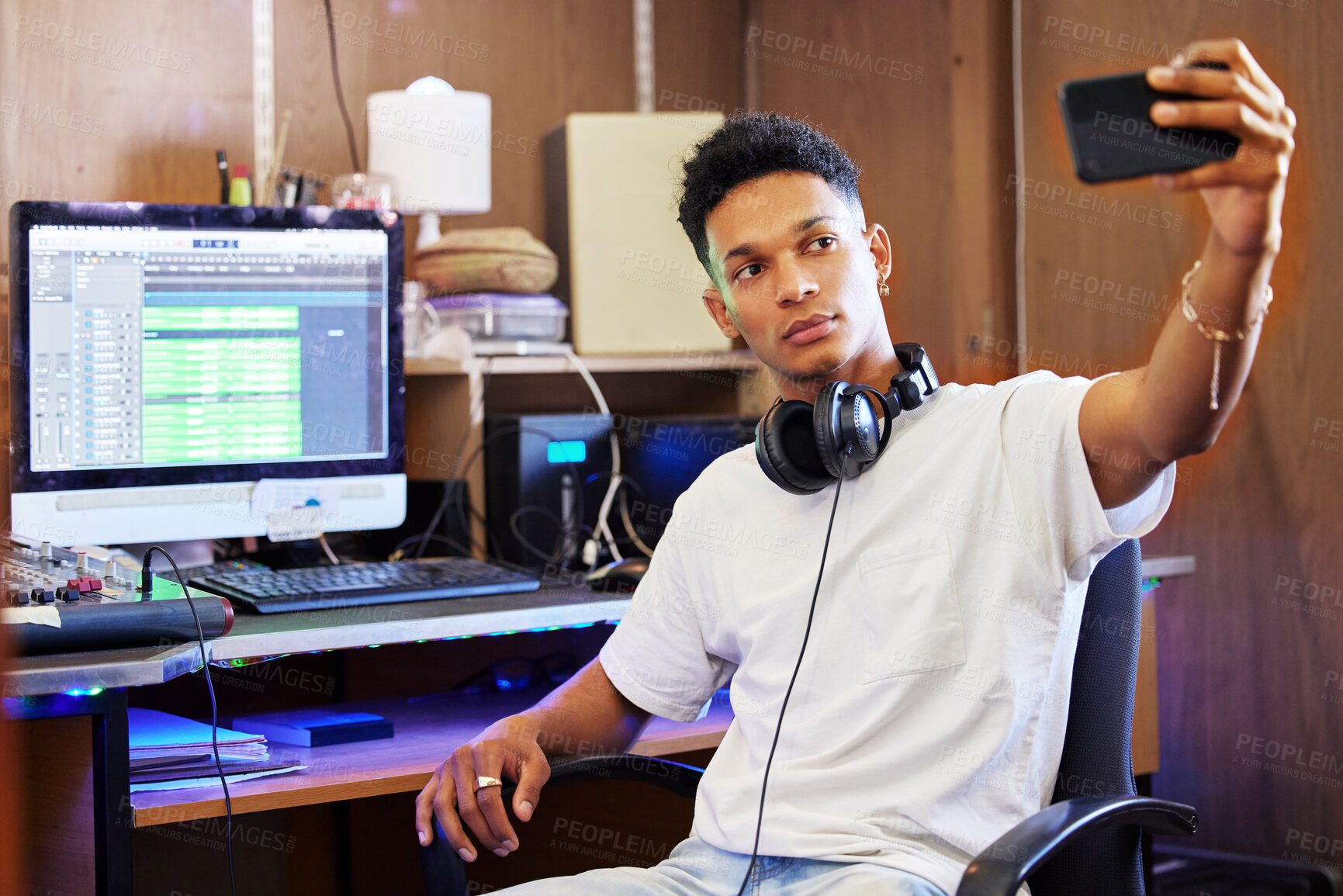 Buy stock photo Cropped shot of a handsome young male music producer taking selfies while working in his home office