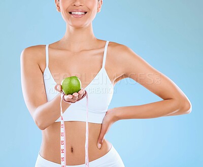 Buy stock photo Girl, studio and apple with tape for diet or fitness goal for slim body, nutrition and wellness in underwear for confidence. Woman, measure and size with fruit for weightloss and blue background.