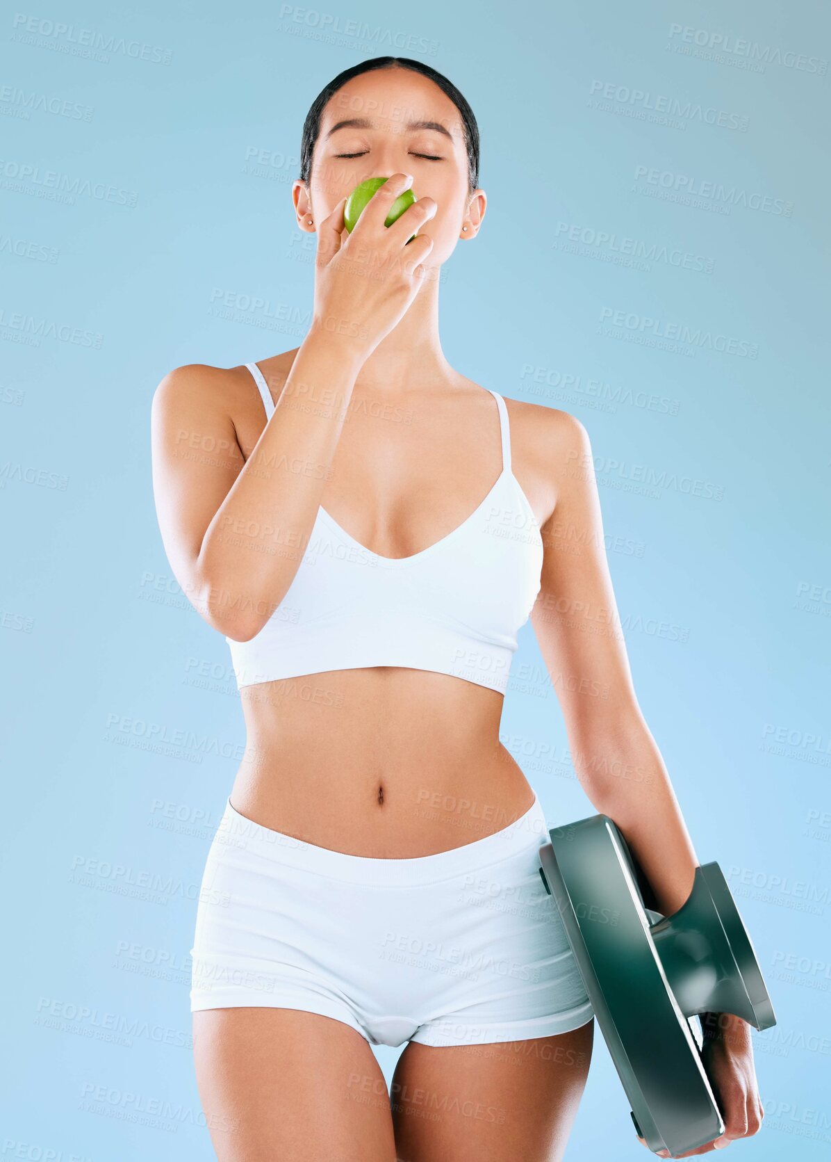 Buy stock photo Body, woman and apple with scale in studio for healthy diet, lose weight or nutrition for wellness. Fitness model, eating or fiber fruit for weightloss progress or measure fat loss on blue background