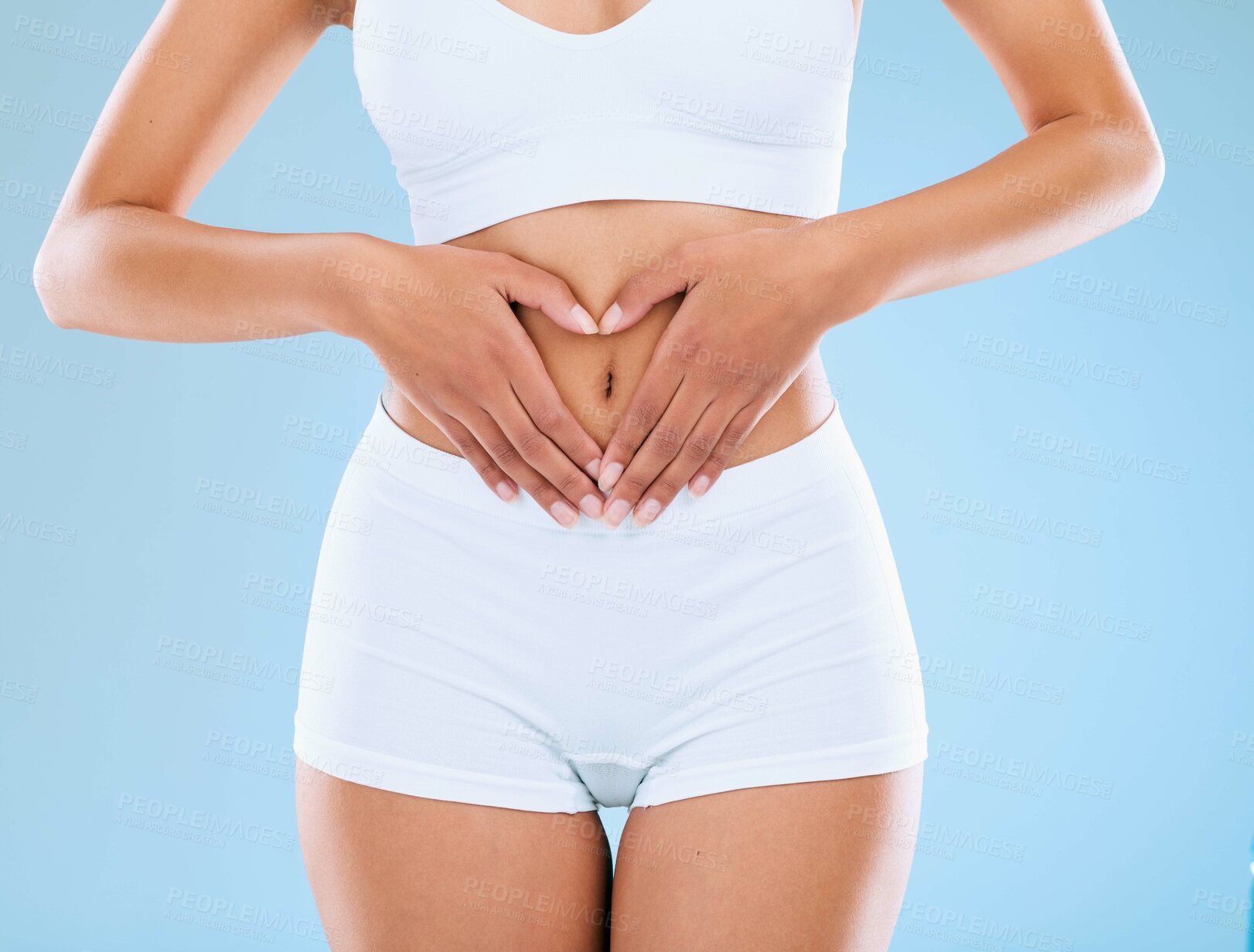 Buy stock photo Woman, heart and hands on stomach in studio for gut health, digestive wellness and nutritional balance for digestion. Girl, love gesture and isolated on blue background for body care and weightloss.