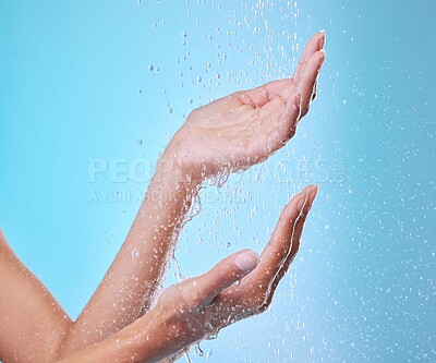 Buy stock photo Hands, woman and water to shower in studio for skin cleaning, body care and hygiene for skincare. Person, morning routine and grooming in bathroom with bathing, washing or wellness on blue background