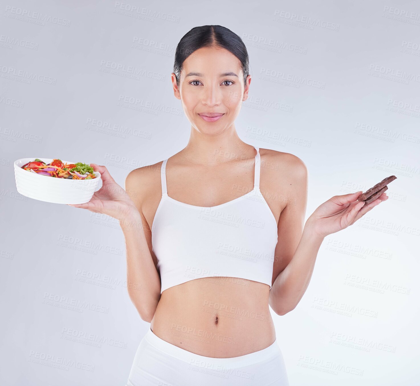 Buy stock photo Portrait, smile and woman with salad and chocolate in studio for diet or nutrition choice. Happy, decision and female person with sweet cacao candy and healthy meal for balance by white background.