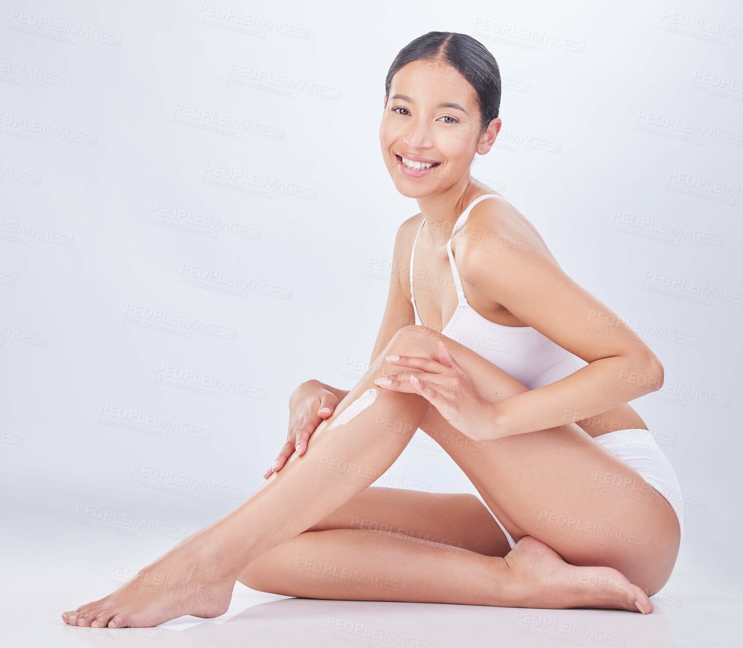 Buy stock photo Beauty, legs and skincare with portrait of model in studio on white background to apply lotion. Body, cream and wellness with happy model on floor for dermatology, hair removal or waxing skin