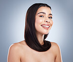 Portrait of a beautiful brunette woman with healthy skin and hair against a grey background. Young mixed race woman with long brown hair smiling and looking at the camera