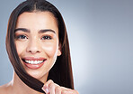 Portrait of a beautiful mixed race woman with clean skin and healthy hair posing against a studio background with copy-space. Woman pulling on her hair to show its strength and showing no breakage