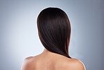 Rear view of brunette woman posing with her hair over her shoulder. Young mixed race woman with healthy smooth straight hair