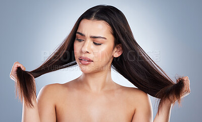 Buy stock photo Frustrated woman, hair and damage with split ends for disaster or haircut on a blue studio background. Upset female person or young model with stress, dry or bristle piece for messy or bad treatment