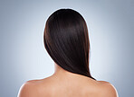 Rear view of brunette woman posing with her hair over her shoulder. Young mixed race woman with healthy smooth straight hair