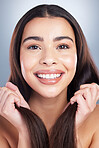 Close up portrait of a beautiful mixed race woman with clean skin and shiny smooth hair posing against a studio background. Woman holding her hair to show off healthy hair care