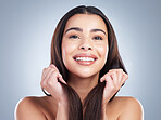 Portrait of a beautiful mixed race woman with clean skin and shiny smooth hair posing against a studio background. Woman holding her hair to show off healthy hair care