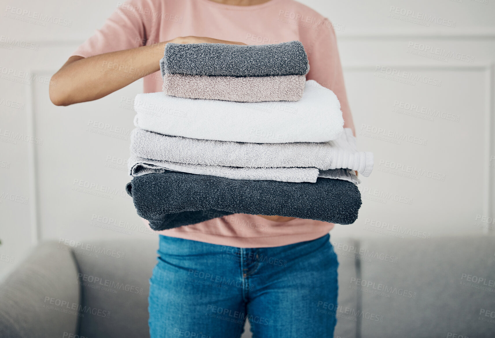 Buy stock photo Towels, hands and cleaning with a woman housekeeper closeup in the living room of a home for hygiene. Laundry, housekeeping and chores with a female cleaner carrying a pile of washing in her house
