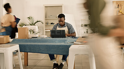 Buy stock photo Sustainable fashion designer, young man and creative working on a laptop in a busy ethical startup, textile workshop and manufacturing studio. Factory worker planning online orders for trendy clothes