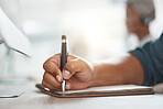 Closeup of one mixed race businessman writing notes in a book while working in at a desk in an office. Hands of entrepreneur planning schedule and brainstorming ideas in journal diary. Staying organised with to do list