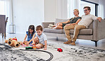 Parents on sofa, happy and watch children with toys on the living room floor and home. Mom relax with dad on couch in lounge, as boy and girl kids have fun together on carpet in family house