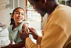 Father, injury and arm bandage for girl after accident in bedroom. First aid, black family and man apply plaster on wound of hurt or injured child for wellness, recovery and healthcare.