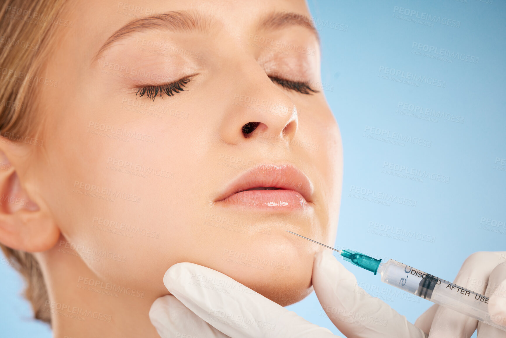 Buy stock photo Woman, studio and injection for lip filler, beauty and anti aging skincare process by blue background. Model, facial plastic surgery and syringe needle with doctor, surgeon or cosmetic expert