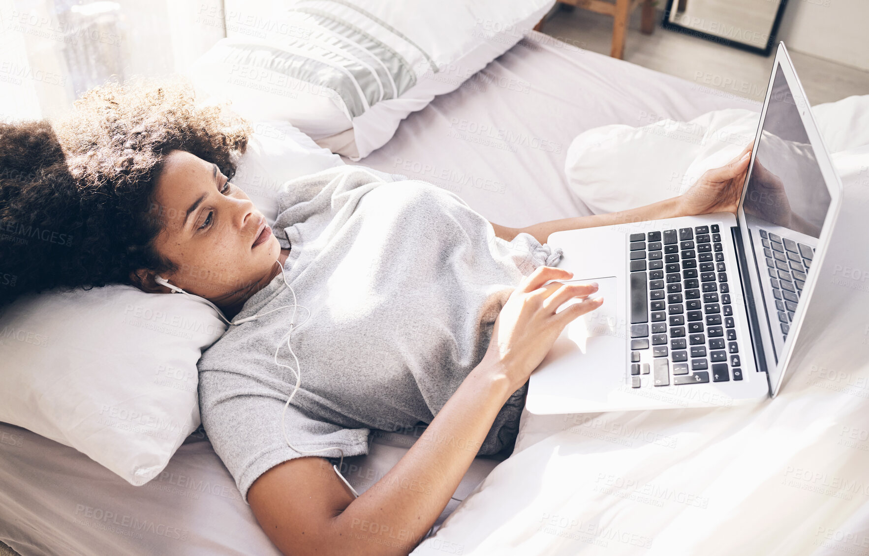 Buy stock photo Music earphones, woman and laptop in bed in bedroom for social media or internet browsing in the morning. Technology, relax or black female with computer for streaming podcast, audio or radio in home