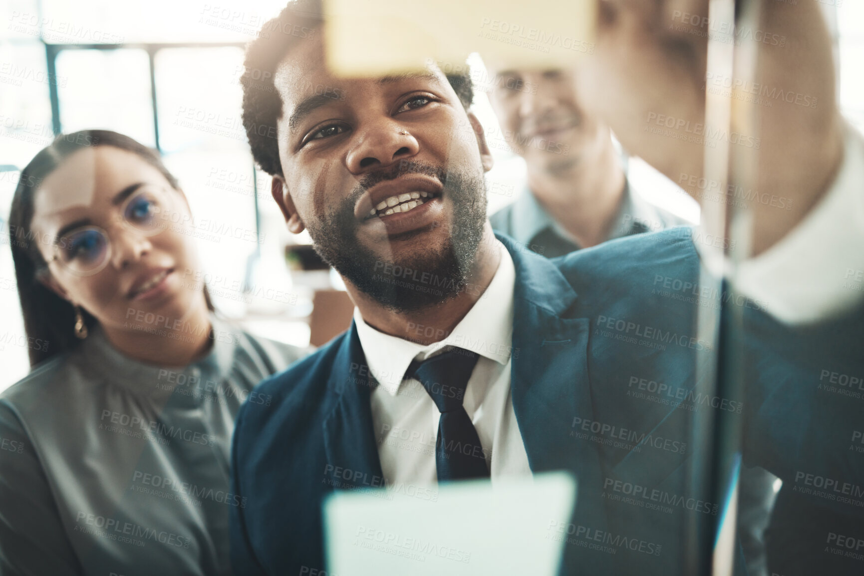 Buy stock photo Businessman, writing and planning schedule, brainstorming or strategy on glass wall at office. Group of employee workers in team project plan, tasks and write on sticky note together