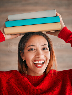 Buy stock photo Reading, portrait and student with books on her head while studying in college for a test or exam. Happy, smile and excited young woman with stories, novels or fiction standing by wall in the library