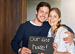 Happy couple, portrait and moving in new home with sign, hug or embrace for love, bonding or apartment. Young man and woman with smile, blackboard or poster for property, investment or house together