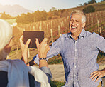 Senior, man and woman with tablet for photography in countryside on holiday for weekend getaway on anniversary date, love and happiness. Couple, together and care in vineyard for memory or retirement