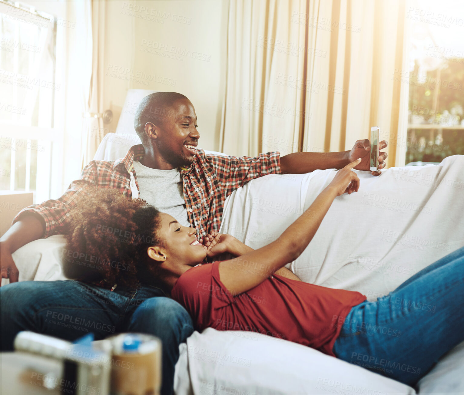 Buy stock photo Home, love and black couple on couch, smartphone and relaxing with social media, lens flare and texting. Apartment, man or woman on sofa, cellphone and sunshine with internet, digital app or marriage