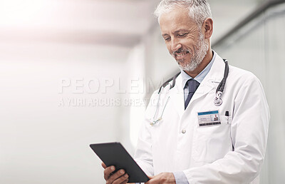 Buy stock photo Doctor, man and reading tablet with app, happy and thinking for solution in corridor at hospital. Mature medic, person and touchscreen for telehealth with smile for results, report and information